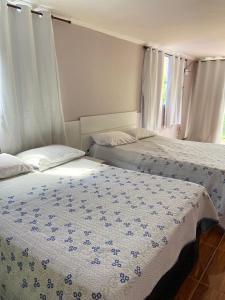 two twin beds in a room with a window at Triplex Costazul Temporada in Rio das Ostras