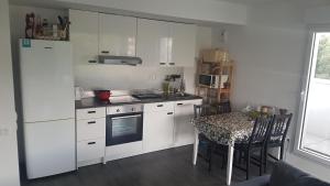 una cocina con armarios blancos y una mesa con sillas. en Appartement entier, en Rennes