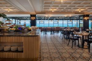 un restaurante con bar, mesas y sillas en Resort Hadera by Jacob Hotels en H̱adera