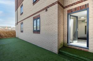a brick wall with a green yard next to a building at Avery House 1 - One Bedroom with Outdoor Terrace in Darlington