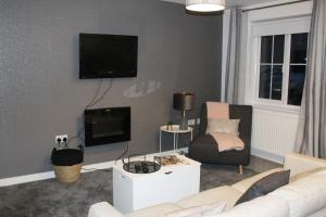 a living room with a white couch and a tv at Penelope Maison - London in 50 Mins, Free Parking, 1 BDRM Home in Peterborough