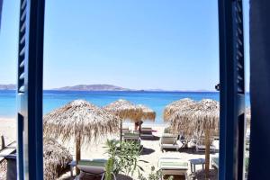 una spiaggia con ombrelloni e sedie di paglia e l'oceano di Meltemi apartment by opus ad Agios Stefanos