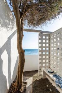 a tree in a room with a view of the ocean at Meltemi apartment by opus in Agios Stefanos