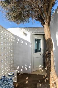 uma garagem branca com uma porta ao lado de uma árvore em Meltemi apartment by opus em Agios Stefanos