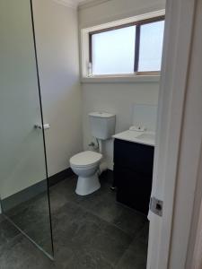 a bathroom with a toilet and a sink and a window at The Rocks Apartments in Halls Gap