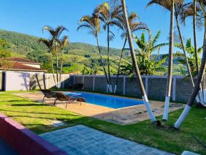 a swimming pool with palm trees next to a house at Chácara Cateto in Socorro