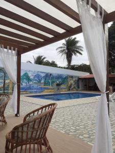 un pabellón con sillas y una piscina con un mural en Chácara de Serra! en Tianguá