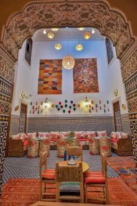 una habitación con sillas, una mesa y un cuadro en la pared en Dar Fes Tresor en Fez