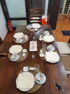 een houten tafel met witte borden en borden erop bij Putra Villa Condo in Kuala Lumpur