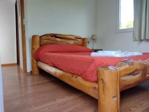 a bedroom with a large wooden bed with red sheets at Cabaña Los Cipreses in San Carlos de Bariloche