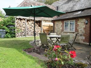 a table and two chairs with a green umbrella at Forge Cottage in West Lulworth