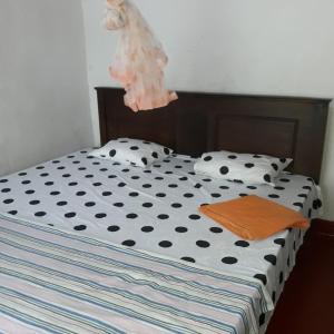 a bed with black and white polka dot sheets and a wooden at Colonial Surfing Villa Hostel & Home Stay in Midigama