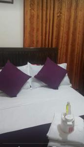 a bed with purple pillows and a bottle on it at Serdena Homestay Fronting Cuatro Islas in Hindang