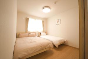 1 dormitorio con 2 camas y ventana en TKD HOUSE FURANO en Furano
