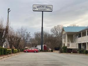 a red car parked in a parking lot with a street sign at El Rancho Motel in Little Rock