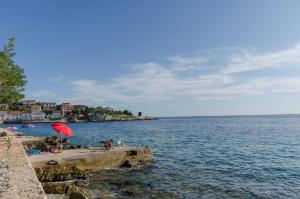 a beach with a red umbrella and the water at Apartment Luna in Lun +14 photos