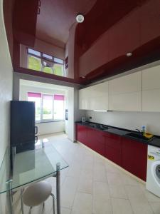 a kitchen with red cabinets and a glass table at вулиця Дмитра Іващенка Апартаменти in Lutsk