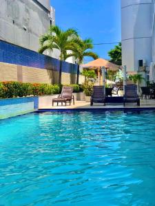 a swimming pool with two chairs next to a building at FLAT 134 - Imperial Flat Tambaú Nobile, beira-mar em João Pessoa in João Pessoa