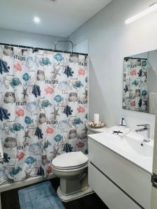 a bathroom with a toilet and a shower curtain at MenPour Apartments Complex in Koolbaai