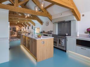 a large kitchen with white counters and wooden ceilings at Butterwell Barn in Hemborough Post