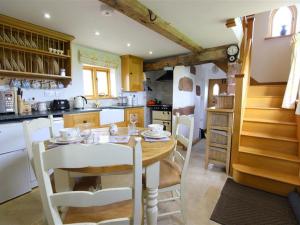 a kitchen with a wooden table and white chairs at The Shooting Folly in Cheswardine