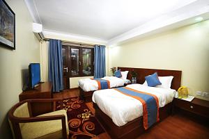 una camera d'albergo con due letti e una televisione di Karma Hotel Nepal a Kathmandu