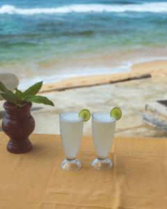 two glasses sitting on a table next to a potted plant at Why Not Guest house in Hikkaduwa