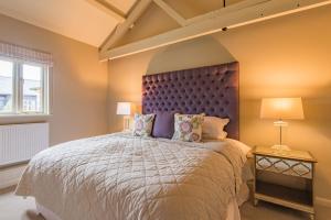 a bedroom with a large bed with a purple headboard at Snipe Barn in Aston