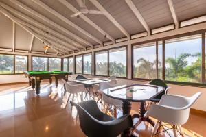 um quarto com mesas, cadeiras e janelas em Mango & Wine by StayVista - Orchard villa with Kids Zone, Gazebo, Pool & Games room em Nashik