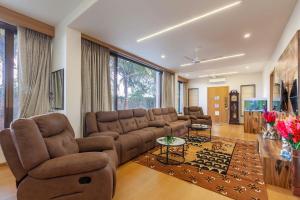 uma sala de estar com um sofá e uma televisão em Mango & Wine by StayVista - Orchard villa with Kids Zone, Gazebo, Pool & Games room em Nashik