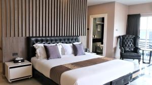 um quarto com uma cama grande e uma cadeira preta em KTK Pattaya Hotel & Residence em Pattaya Central