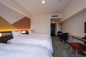 a hotel room with two beds and a desk at Hotel Kanazawa in Kanazawa