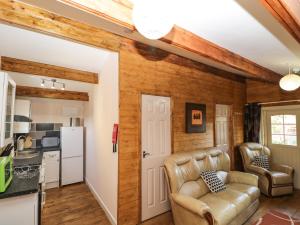 a living room with a couch and a kitchen at The Log Cabin in Swindon