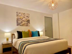 a bedroom with a large bed with colorful pillows at UNWND Residences Dumaguete in Dumaguete