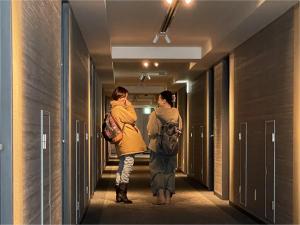 two people walking down a hallway at Hotel Kanazawa in Kanazawa