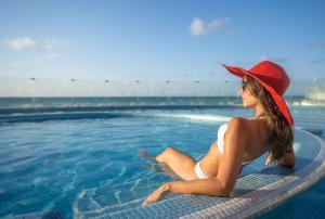 a woman in a red hat sitting in a swimming pool at Playacar Palace - All Inclusive in Playa del Carmen