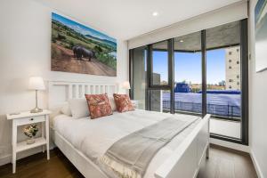 a bedroom with a white bed and a large window at Luxury African themed apartment☆10min to MCG & Swan St☆On-site Parking☆Balcony☆Rooftop deck☆Gym☆ in Melbourne