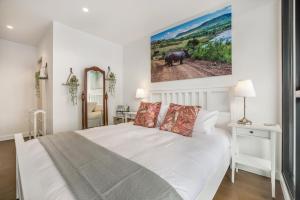 a bedroom with a white bed and a picture of a elephant at Luxury African themed apartment☆10min to MCG & Swan St☆On-site Parking☆Balcony☆Rooftop deck☆Gym☆ in Melbourne