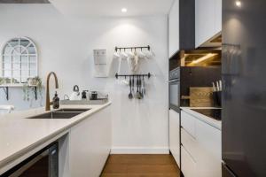 a white kitchen with a sink and a stove at Luxury African themed apartment☆10min to MCG & Swan St☆On-site Parking☆Balcony☆Rooftop deck☆Gym☆ in Melbourne