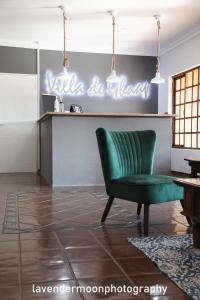 Villa de Ghaap Guesthouse في Douglas: كرسي أخضر في غرفة المعيشة مع علامة نيون