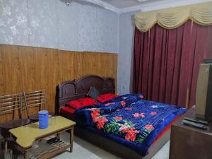 a bedroom with a bed with a blue blanket and a table at SUMAN GUEST HOUSE in Katra