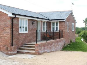 a brick house with a fence and stairs in front at The Tractor Shed in Shaftesbury