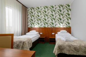 ポズナンにあるHotel Zielonyのベッド2台と壁紙が備わるホテルルームです。