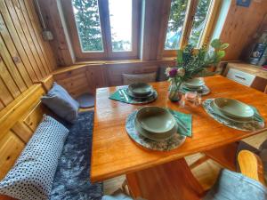 une table dans une petite maison avec des assiettes et des fleurs dans l'établissement Chalet Košutnik Velika planina, à Kamniška Bistrica