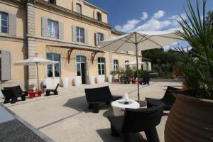 une terrasse avec des chaises, une table et un parasol dans l'établissement Hotel Estelou, à Sommières