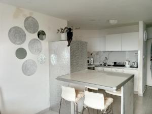 a kitchen with a table and white cabinets and white chairs at 123Eilat tzofit in Eilat