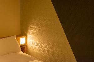 a bedroom with a bed and a wall with a white wall at Hotel Kanazawa in Kanazawa