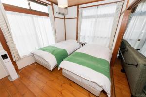 two beds in a room with windows at Leaf in Kamakura