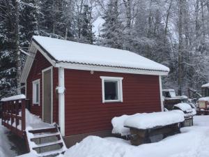 Cabaña roja con nieve en el techo en puhkemajake, en Rõuge