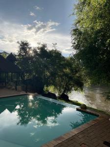 a swimming pool with the sun reflecting in the water at River Rock Lodge in Parys